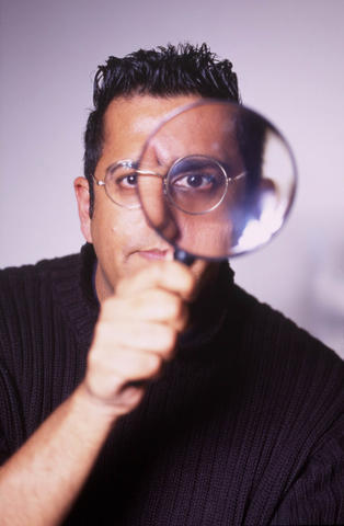 Photo of S. Singh looking through a magnifying glass