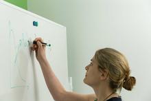 Photo of G. Stirling writing formulae on a whiteboard